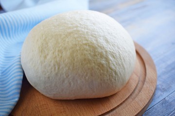 Dough for making delicious cinnamon buns on wooden background.