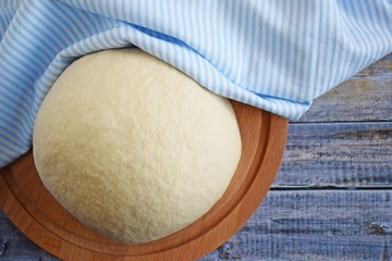 Dough for making delicious cinnamon buns on wooden background.