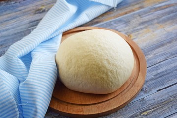 Dough for making delicious cinnamon buns on wooden background.
