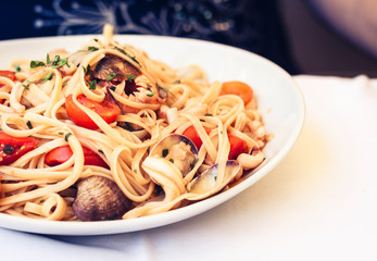 Seafood pasta spaghetti linguine wish mussels, clams, cherry tomatoes, fresh parmesan on the white plate in restaurant in Catania, Sicily, Italy.