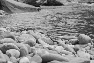 Steine am Wasser in schwarz weiss mit unschärfe