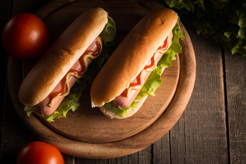 Photo of barbecue grilled hot dog with yellow mustard and ketchup on wooden background. Hot dog...