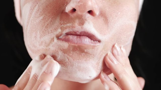 Close-up of a woman's face. The girl applies a cleansing agent and massages her. Concept of facial skin care, beauty, and care.
