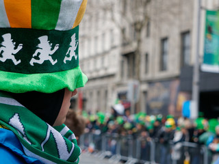 Naklejka premium Niezidentyfikowany mężczyzna w wielkim świątecznym zielonym kapeluszu z okazji Dnia Świętego Patryka. Ludzie zbierają się i czekają na ulicach Dublina w Irlandii na paradę.