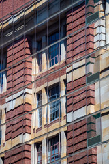 Reflection of brick building in modern skyscraper facade with reflective windows