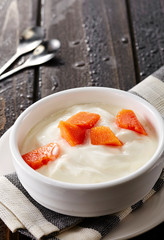 Bowl of fresh mixed berries and yogurt with farm fresh Papaya and blueberry on a wooden table
