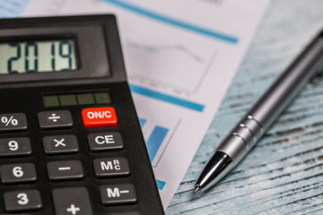 Calculator with 2019 digits lie on financial document with pen on the wooden table