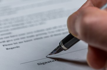 Close-up of a man hand signing on financial document  