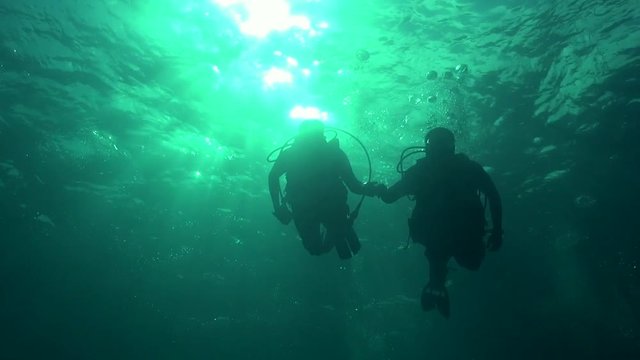 Divers silhouette against sun ball