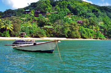 A rustic white and black fishing boat storing a seine net with orange floats and yellow rope, and...