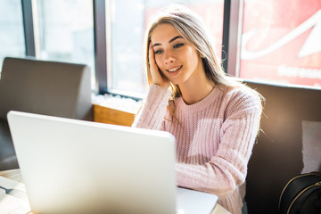 Beautiful young woman using laptop at cafe look at screen