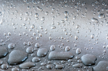 water droplets lie on a silvery metal surface