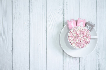 Pink square wood with white numbers 1 and 4.Gray square wood with white letters FEB.February 14 Valentine's Day.White coffee cup on wooden floor.