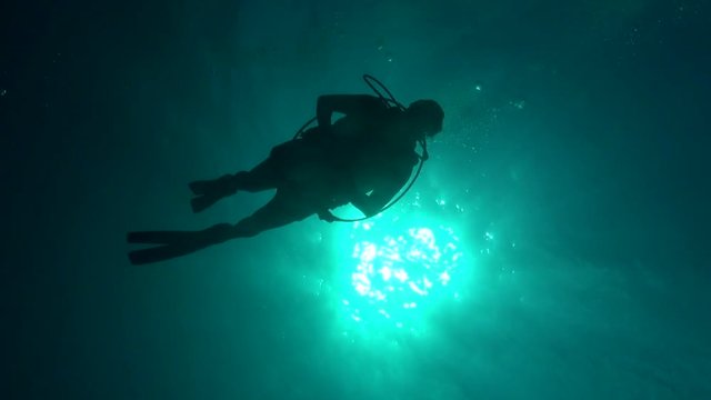 Diver silhouette against sun ball