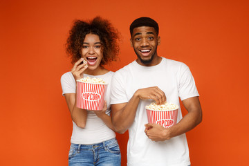 Man and woman eating popcorn on orange background - Powered by Adobe