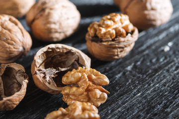 Whole walnuts and their kernels on a wooden dark table close-up with copyspace