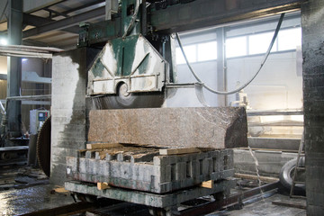 Granite processing in manufacturing. Cutting granite slab with a circular saw. Use of water for cooling. Industrial sawing of granite