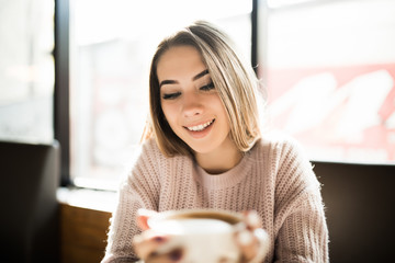 Young Woman holding cup drinking coffee in a cafe