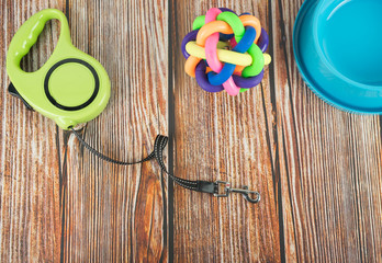 Pet accessories concept.  Pet leashes with rubber toy and bowl on wooden background.