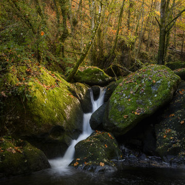 A waterfall rushes between huge boulders