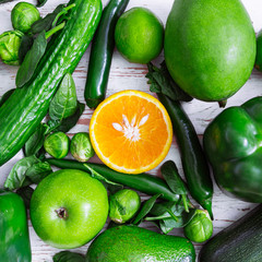 be different concept. orange surrounded by green fruits and vegetables. overhead view