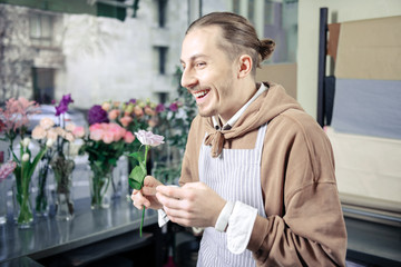 Positive delighted male person holding tender flower