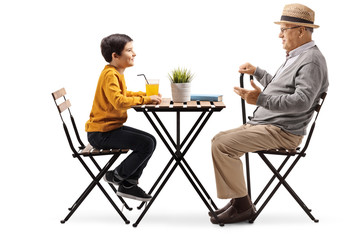 Mature man sitting at a coffee table and talking to his grandson