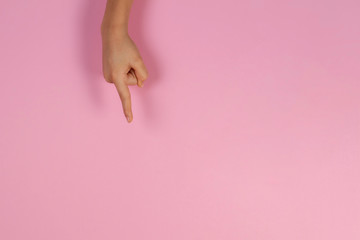 Kid hand pointing on pastel pink background