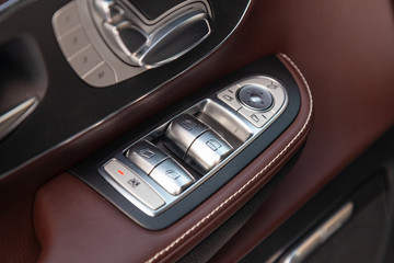 Fototapeta na wymiar The interior elements of a new expensive business car inside with windows and seats buttons and the leather with wood and chrome