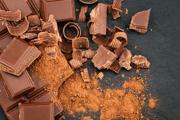 Broken chocolate pieces and cocoa powder on a dark background