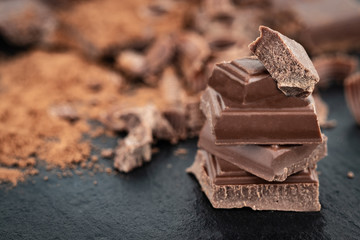 Broken chocolate pieces and cocoa powder on a dark background