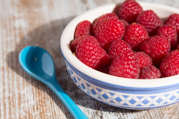 Bowl of raspberries on wooden background