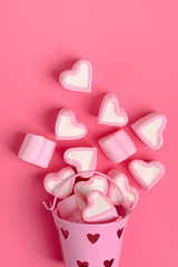 marshmallows  heart shaped candies spilled from a pink iron bucketon a pink background Happy Valentine's Day Flat lay Top view