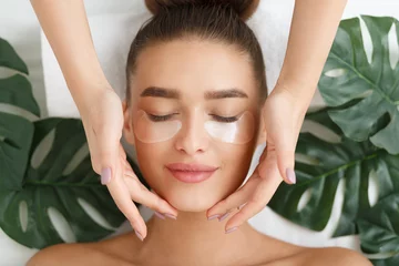 Foto op Plexiglas Woman with eye patches having face massage © Prostock-studio