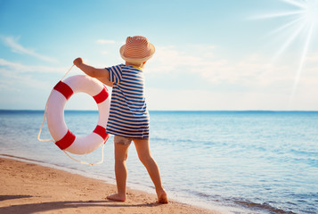 little boy playing at the beach in hat