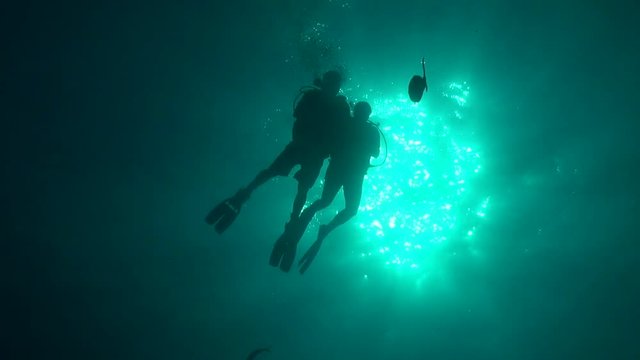 Divers silhouette against sun ball