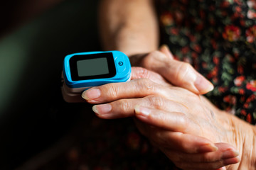 Old lady measuring her oxygen saturation with a pulse oximeter