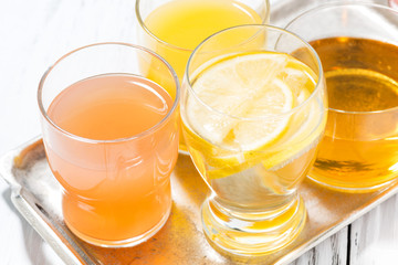 assortment of fresh citrus juices in glasses on white table, top view closeup