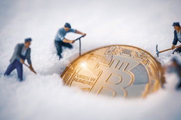 macro miner figurines digging snow to uncover big shiny bitcoin. cryptocurrency concept