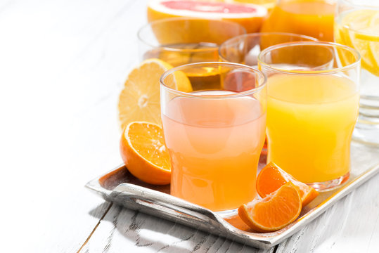 assortment of fresh citrus juices on white table, closeup