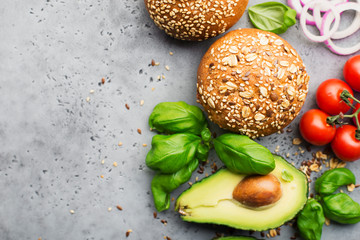 Healthy food. Veggie burger ingredients cereal buns, avocado, cherry tomatoes, basil, sweet onions on a light gray background. Top view, space.