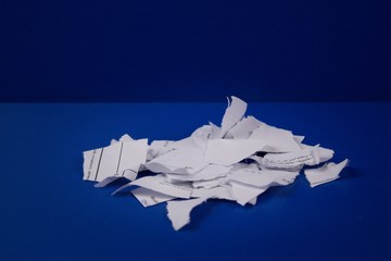 Pieces of torn paper with text on a blue background.Small pile with white paper. Recycling.