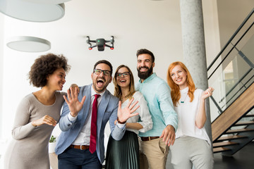 Young happy business people letting the drone camera to fly over the office and having fun