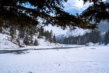 Winter scene of Bow Falls in Banff National Park with an open river, snow and ice.