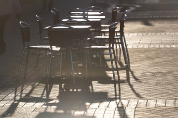 Fototapeta na wymiar empty set of tables and chairs outside a cafe glistening in the early morning sun