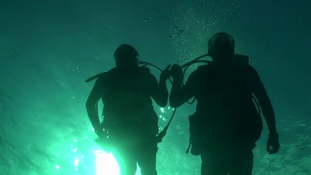 Divers silhouette against sun ball
