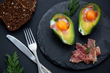 baked avocado with an egg on a black background