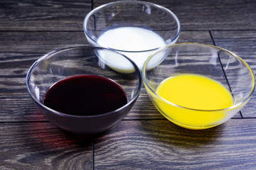 Liquids of different colors in glass plates on a wooden table.