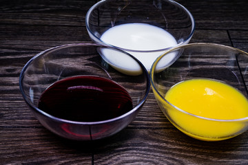 Liquids of different colors in glass plates on a wooden table.