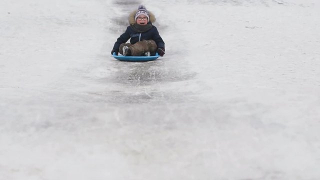 The boy rolls on a sledge in the winter